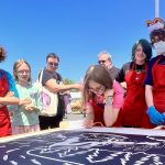 A group of people sign a print.