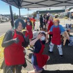 A group of teens wearing red aprons smile and pose for the camera.