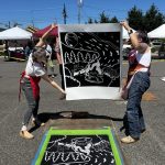 Two people hold up a print.