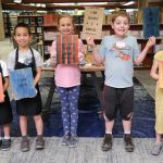 A group of five kids proudly display their letterpress prints.